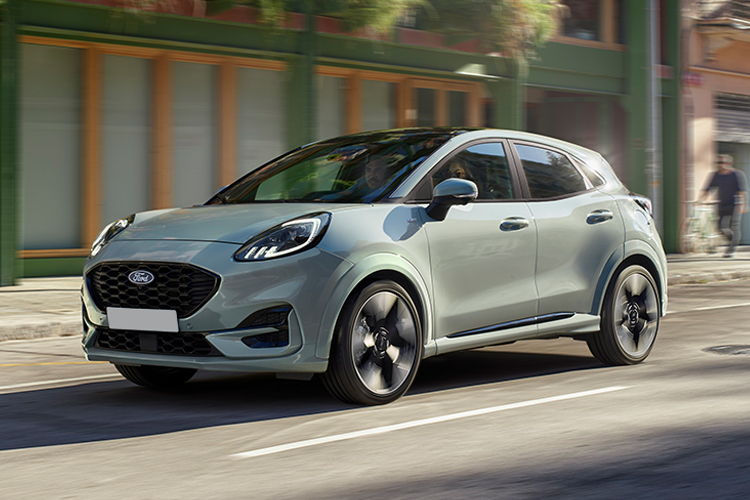 Grey Ford Puma driving down a road.